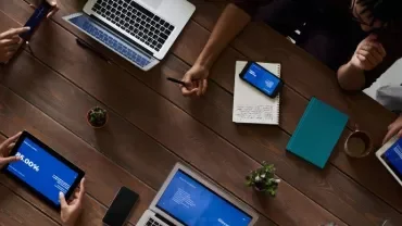 Persone lavorano attorno a un tavolo con laptop e tablet
