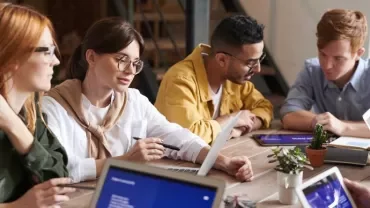 Gruppo di colleghi al lavoro su un progetto al tavolo.
