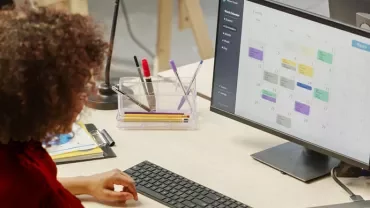 Persona che lavora al computer con calendario sullo schermo.