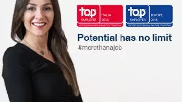 Donna in piedi con sfondo bianco, insegne Top Employer.