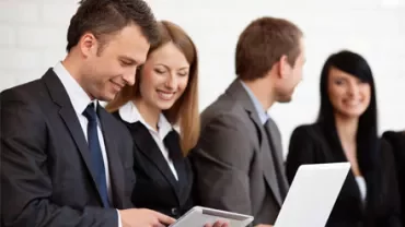 Persone in abiti formali lavorano su laptop e tablet.