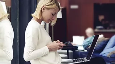 Persona al lavoro con un laptop e uno smartphone.