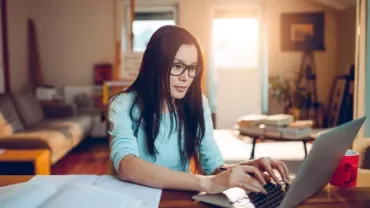 Persona che lavora concentrata al computer in una stanza luminosa