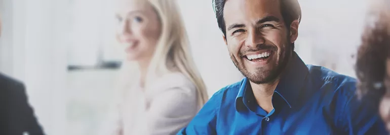 Persona sorridente con camicia blu in un ambiente professionale.