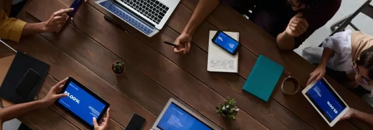 Persone lavorano attorno a un tavolo con laptop e tablet