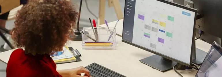Persona che lavora al computer con calendario sullo schermo.