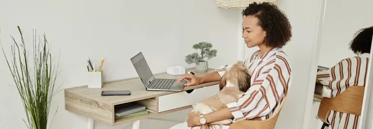 Persona al computer con un cane in grembo.
