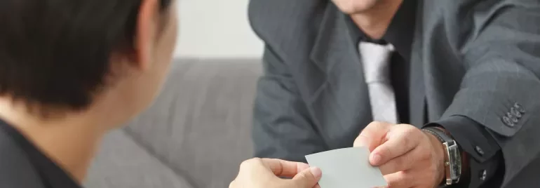 Persona consegna un biglietto da visita in un incontro formale.