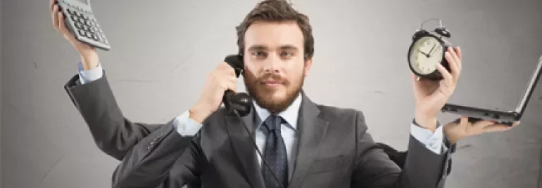 Persona multitasking con calcolatrice, telefono, orologio e laptop.