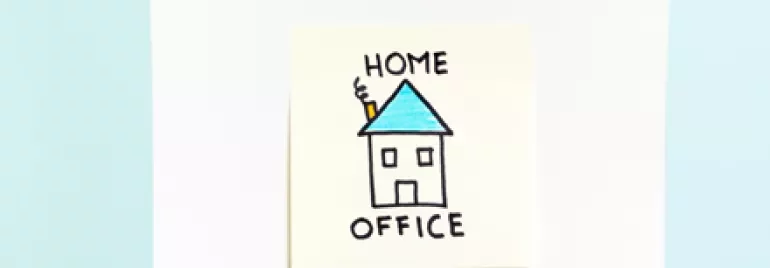 Disegno di una casa con tetto blu su un foglio bianco tenuto da una mano.