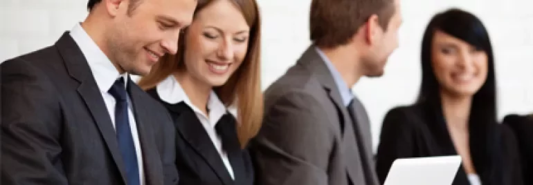 Persone in abiti formali lavorano su laptop e tablet.