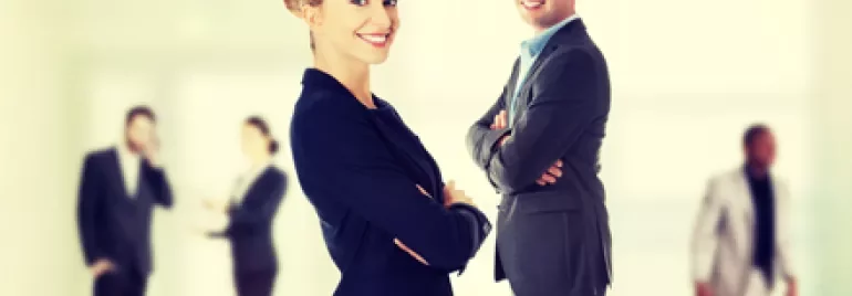 Due persone vestite in abiti formali sorridono davanti.