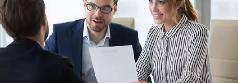 Persone sedute a un tavolo discutendo un documento in ufficio.