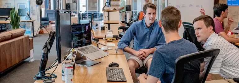 Persone in ufficio moderno discutono intorno a un tavolo.
